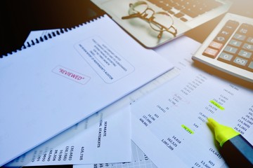 The reviewed financial statement, eyeglass, highlight pencil, calculator, laptop and edited paper. It's important work of the account, finance, internal and external audit must to accurate and timely