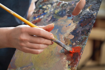 Close up on painter with her palette and brush painting many colours