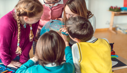 Pupils and teacher in geography class studying a globe