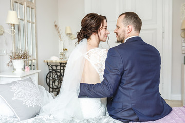 loving couple of newlyweds with bouquit sit in bedroom