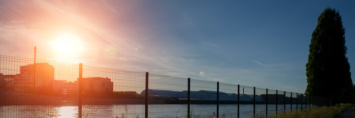 Fence of the embankment on the river bank in the evening in an urban environment. . Web banner.