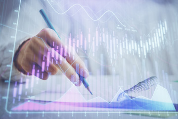 Financial forex graph displayed on hands taking notes background. Concept of research. Double exposure