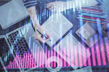 Financial chart drawn over hands taking notes background. Concept of research. Double exposure