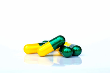 The yellow-green capsules are stacked together on a white background. The concept of health maintenance.