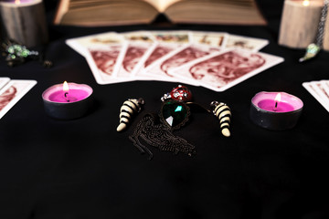 Candles and old tarot cards on black silk. Halloween and fortune telling concept. Mystic background with occult and magic objects on witch table.