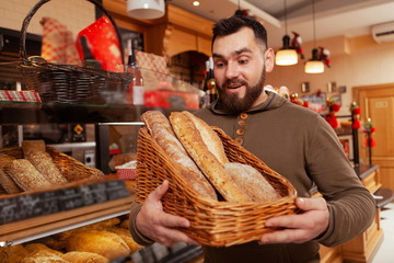 Young man choosing fresh bread from the basket at the bakery. Happy man buying bread at bakehouse
