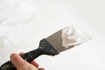 the spatula and the wall with wet plaster