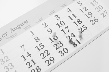Black and white monthly calendar on table with office supplies