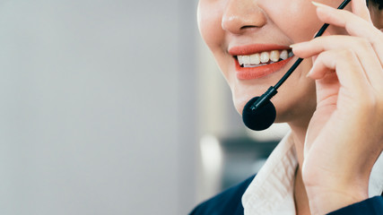 Obraz na płótnie Canvas close up of Asian young beautiful woman staff at service desk talking on hands-free phone in a call centre, female operator agent with headsets, customer service or technical support concept