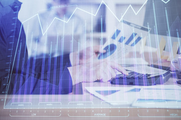 Double exposure of graph with man typing on computer in office on background. Concept of hard work. Closeup.