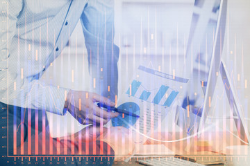 Double exposure of chart with businessman typing on computer in office on background. Concept of hard work.