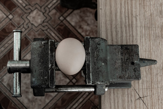 An Egg Cracking Under Pressure Applied By Squeezing Clamps Form The Sides.