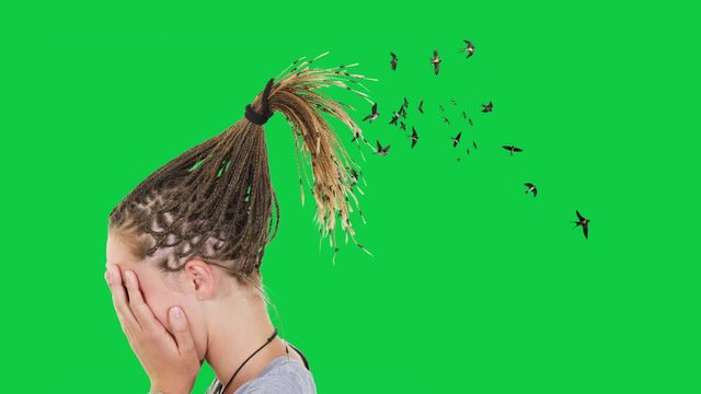Girl covers her face as the swallows come out of her braids on the green screen
