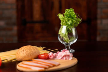 Ingredients for sandwich: lettuce, bacon, tomatoes, bun.