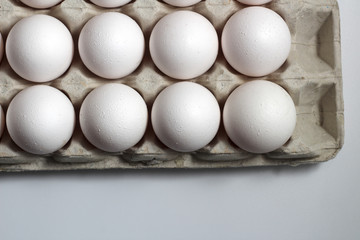 An isolated tray of eggs from recycled materials with white eggs on a white background. Top view