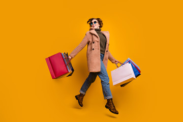 Full body profile photo of pretty shopper lady walk shopping center carry many packs wear sun specs casual pink coat pullover jeans leopard print shoes isolated yellow color background
