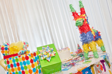 Group of gifts and birthday cake on table