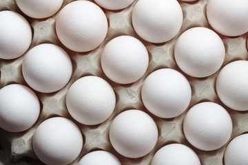 An isolated tray of eggs from recycled materials with white eggs on a white background. Top view