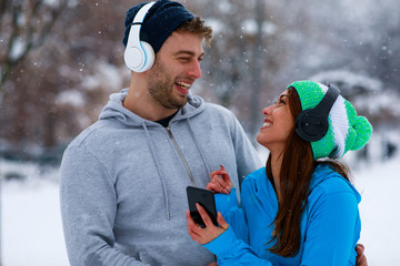 Young sports couple resting after jogging on snowy day in the city