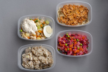 4 lettuce in molds for fast delivery. Pasta with minced meat and onion in navy-style and a jar of vinaigrette on a gray background.