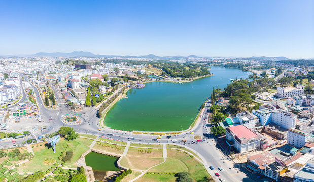 Aerial view of Da Lat city beautiful tourism destination in central highlands Vietnam. Clear blue sky. Urban development texture, green parks and city lake.