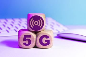 Icône 5G écrit sur des cubes en bois devant un clavier et un écran d'ordinateur - Réseau mobile de 5e génération