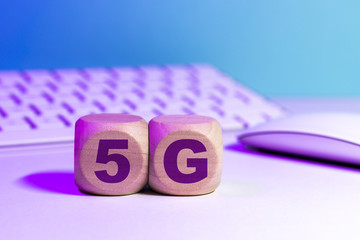 Icône 5G écrit sur des cubes en bois devant un clavier et un écran d'ordinateur - Réseau mobile...