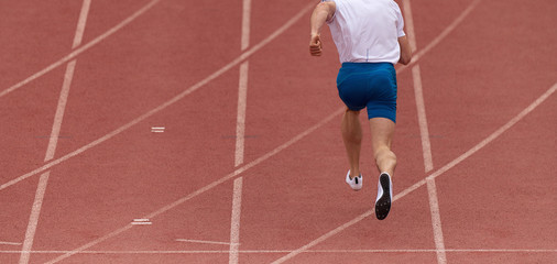 Fototapeta premium Male athlete running on stadium track, dynamic run of sprinter in a stadium