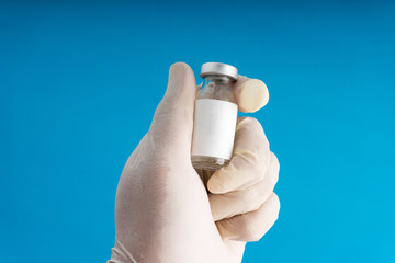 Close up image of surgeon's hand holding a medication vial.