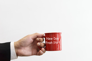Businessman holding a red mug with text new day fresh start.