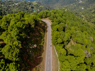 Fototapeta na wymiar Aerial view of a vehicle on the road through a deep forest. Bird eye view of a Green Forest road. Drone shot.