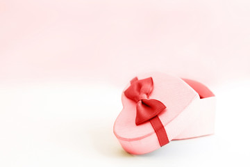 gift box in the form of a heart with a red bow on a white  and pink background. place for your text