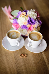 Close up of engagement rings, rose flower bouquet and coffee on table. 