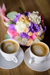 Close up of engagement rings, rose flower bouquet and coffee on table. 