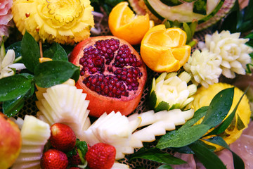 Pomegranate, orange and strawberry in the form of beautiful flowers for table decoration, carving with vegetables and fruits