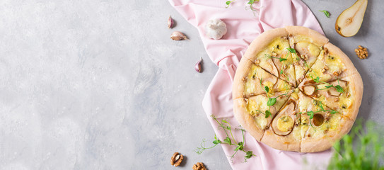 Obraz na płótnie Canvas Pizza banner. Delicious pizza with pear, mozzarella, blue cheese, walnuts and microgreen on gray table. Top view, copy space. Italian cuisine. Recipe, spring menu, banner concept