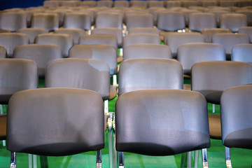 Fototapeta premium Rows of black chairs in the hall on a green background