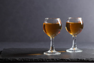 Glass of whiskey on a black stone slate board on black background. Side view, copy space.