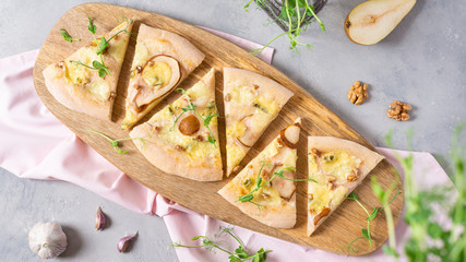 Spring veggie pizza slices with pear and gorgonzola, mozzarella and microgreen on a gray table with ingredients. Top view. Pizzeria, restaurant, menu, banner, recipe concept