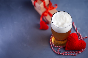 A glass of light beer for Valentine's day, a red heart and gifts copy space