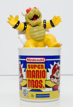 london, england, 05/05/2018 a super mario official nintendo 1990s super mario bros mug coffee cup and bowser toy isolated on a white background. official merchandise.