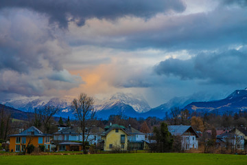 European village dramatic landscape scenic view in twilight sunset evening time landmark scenic view cloudy moody gray sky and Alps mountain background with orange sun lighting