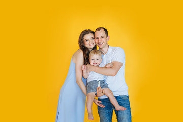 Portrait of beautiful happy family - young parents and their cute little toddler baby son hugging,...