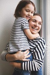 Happy young mother holding adorable girl child on her hands and laughing