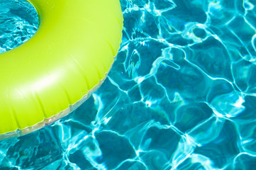 Brightly colored pool ring floating on dappled turquoise water in tropical sun