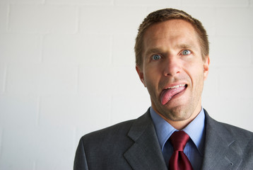 Overwhelmed businessman sticking his tongue out with a confused expression