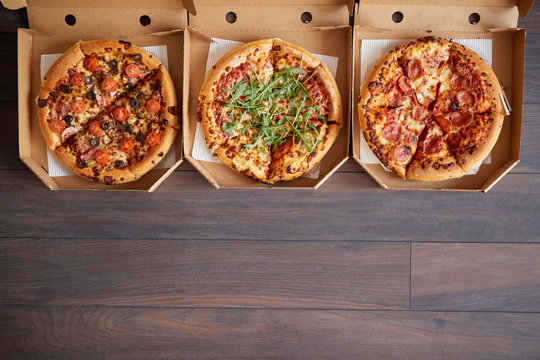 Three different kind of pizzas in delivery boxes