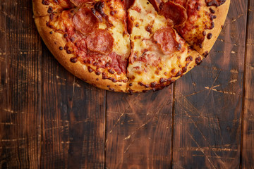Fluffy pepperoni pizza in american style placed on rusty old wooden table