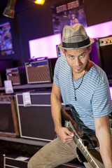 Portrait of young man playing electric guitar in music store