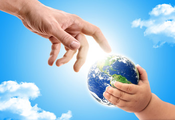 Hand of an adult handing over planet earth to  a baby